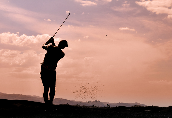 golf ball falling into hole with man in background