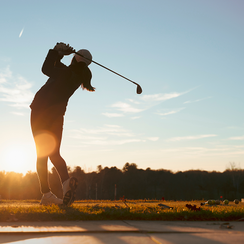 golf ball falling into hole with man in background